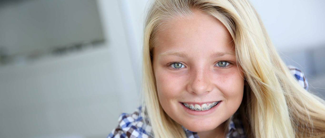 A smiling young woman with blonde hair and blue eyes looking directly at the camera.