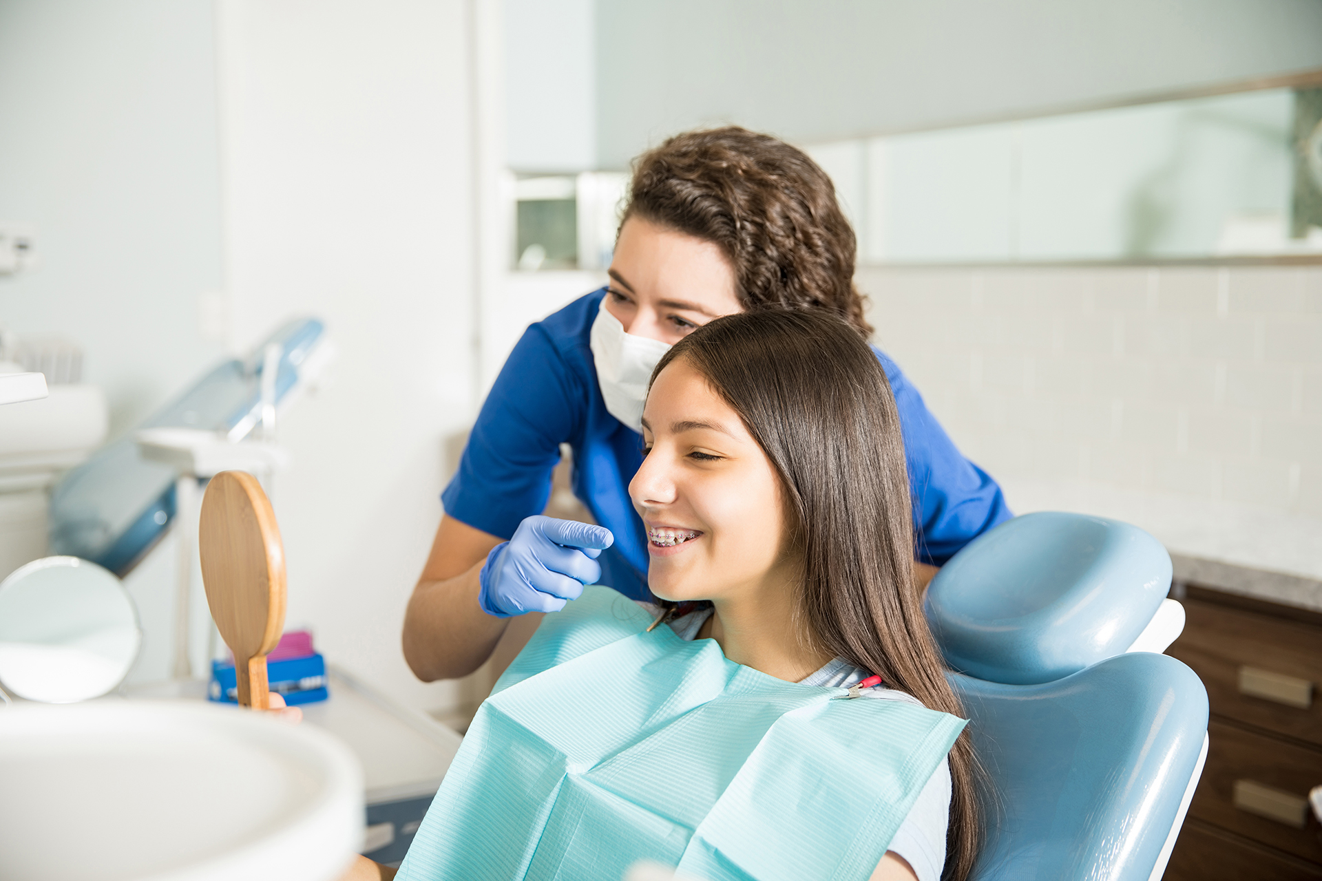 An image featuring a dental hygienist assisting a patient with a tooth cleaning procedure in an office setting.